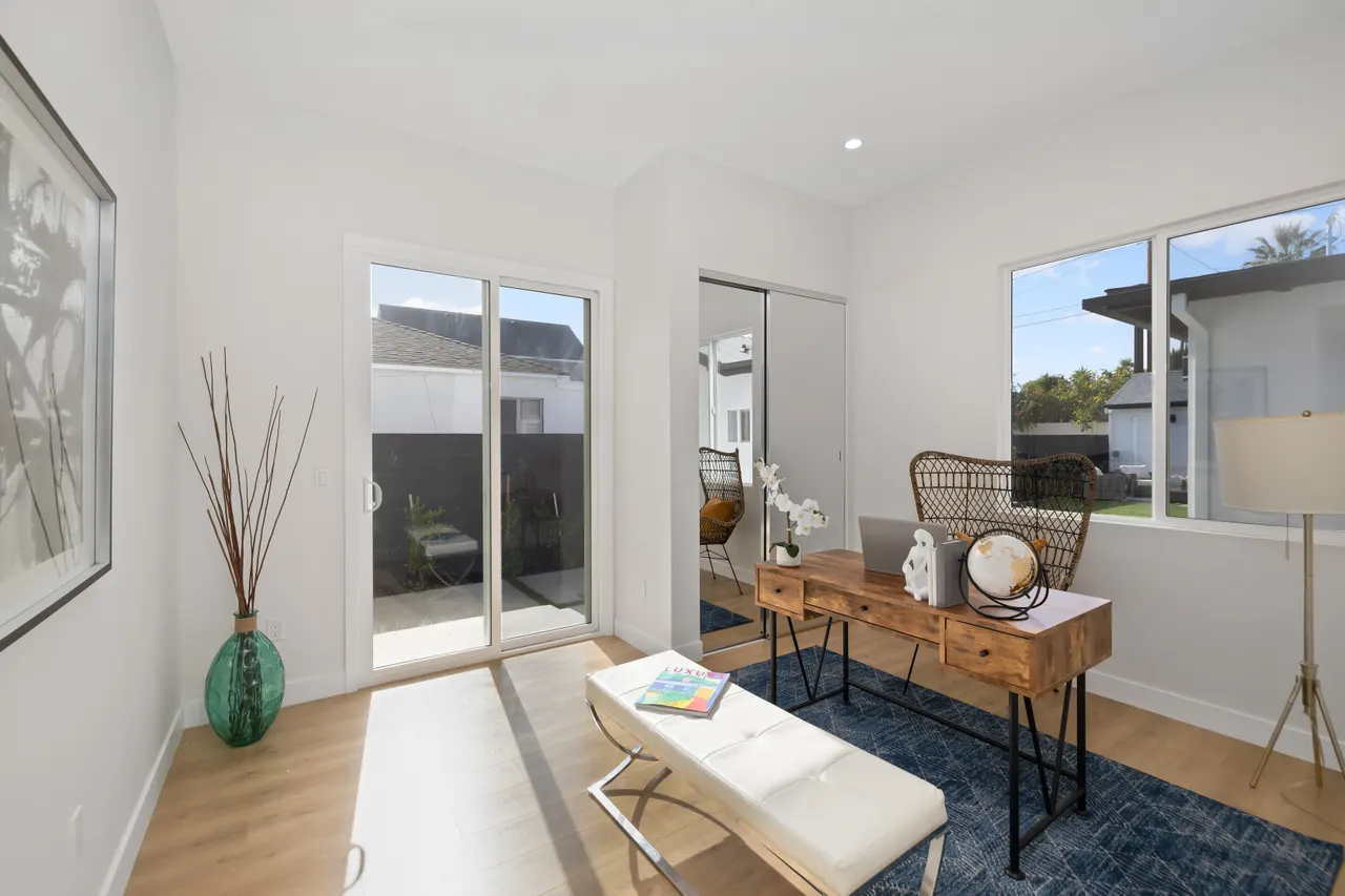 Small sitting nook off the entry with a console table and decor, a tufted bench, a blue area rug, and a sliding glass door bringing in natural light