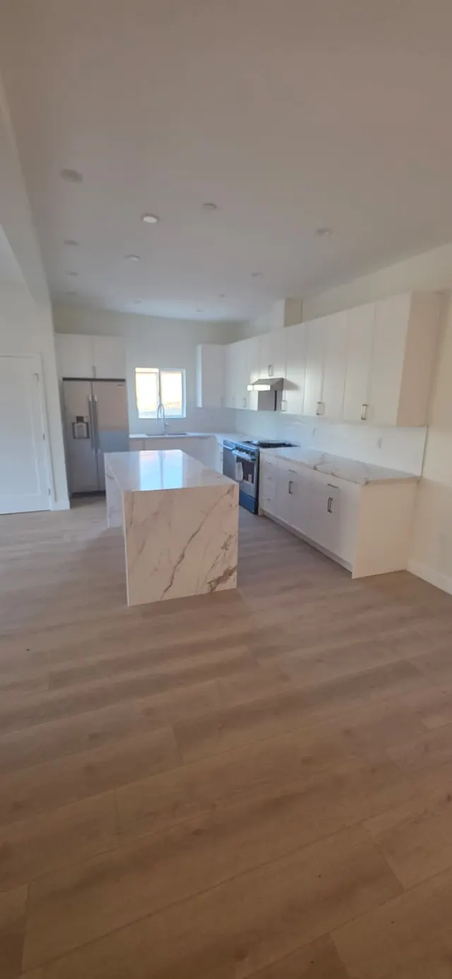 Kitchen with stainless refrigerator, gas range, subway tile backsplash, and marble waterfall island