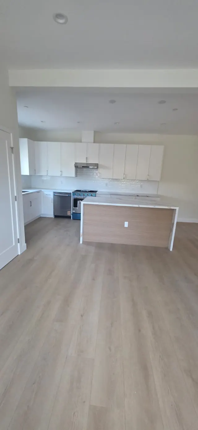Open-concept kitchen viewed from the entry hallway, with white cabinetry, range, and island