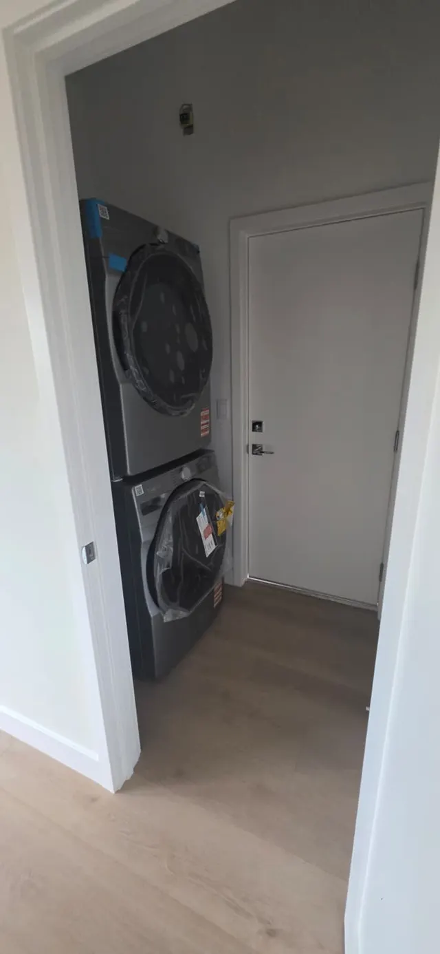 Laundry closet with a stacked washer and dryer, still wrapped in manufacturer packaging