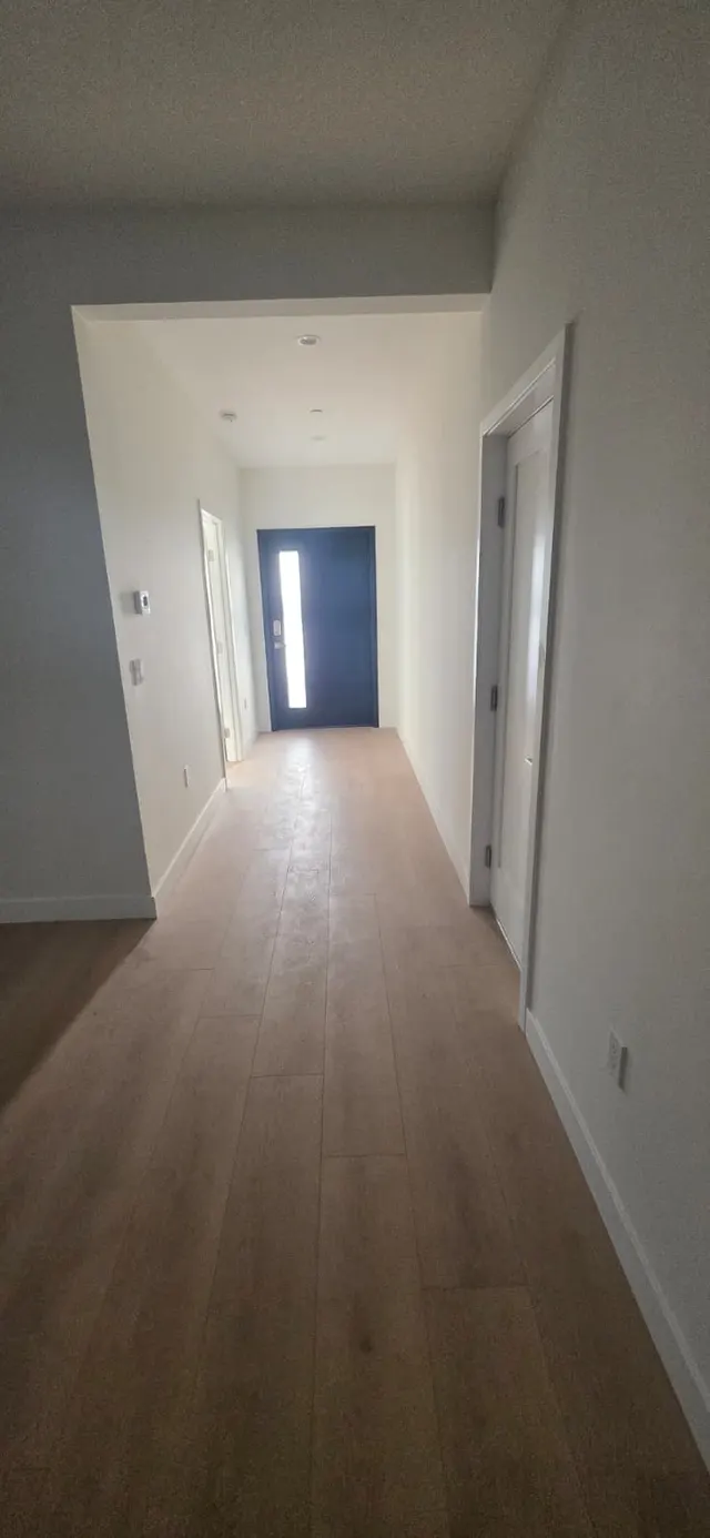 Hallway with wood-look flooring leading to the navy front door