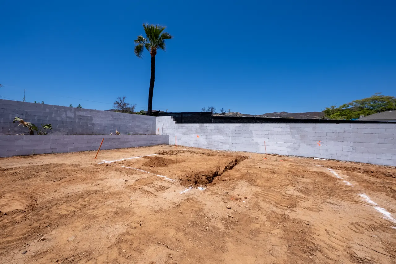 Ground-level detail of the retaining wall corner with string lines and stakes marking out the foundation layout