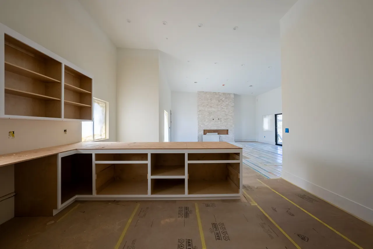 Built-in cabinetry and bookcase millwork in the living area, shown as an unfinished plywood carcass awaiting doors and finish
