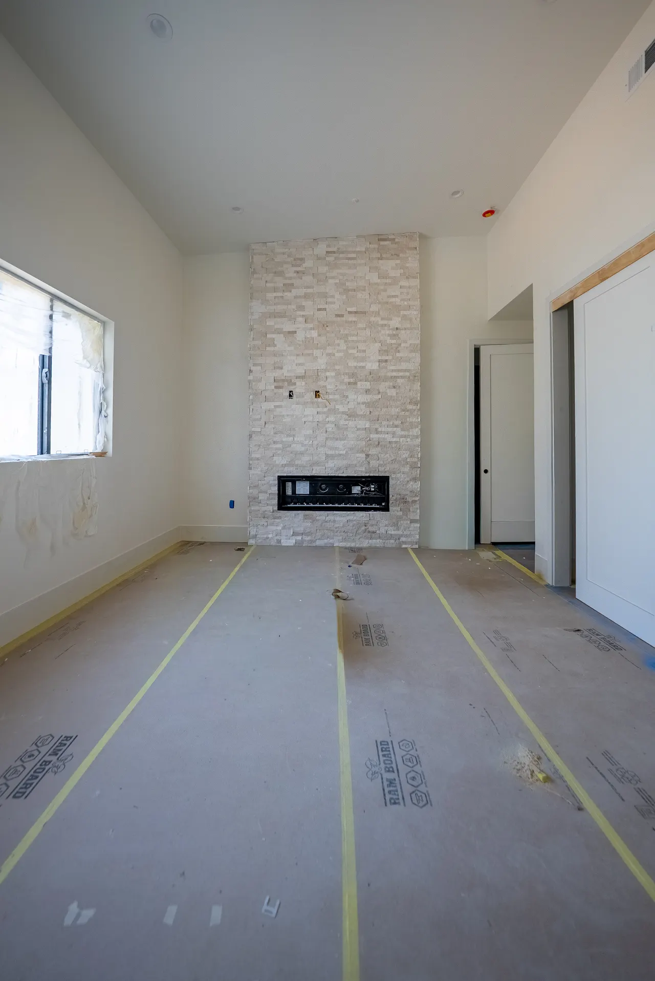 Living room with a floor-to-ceiling stacked-stone fireplace, white paneled sliding closet doors, and a hallway opening