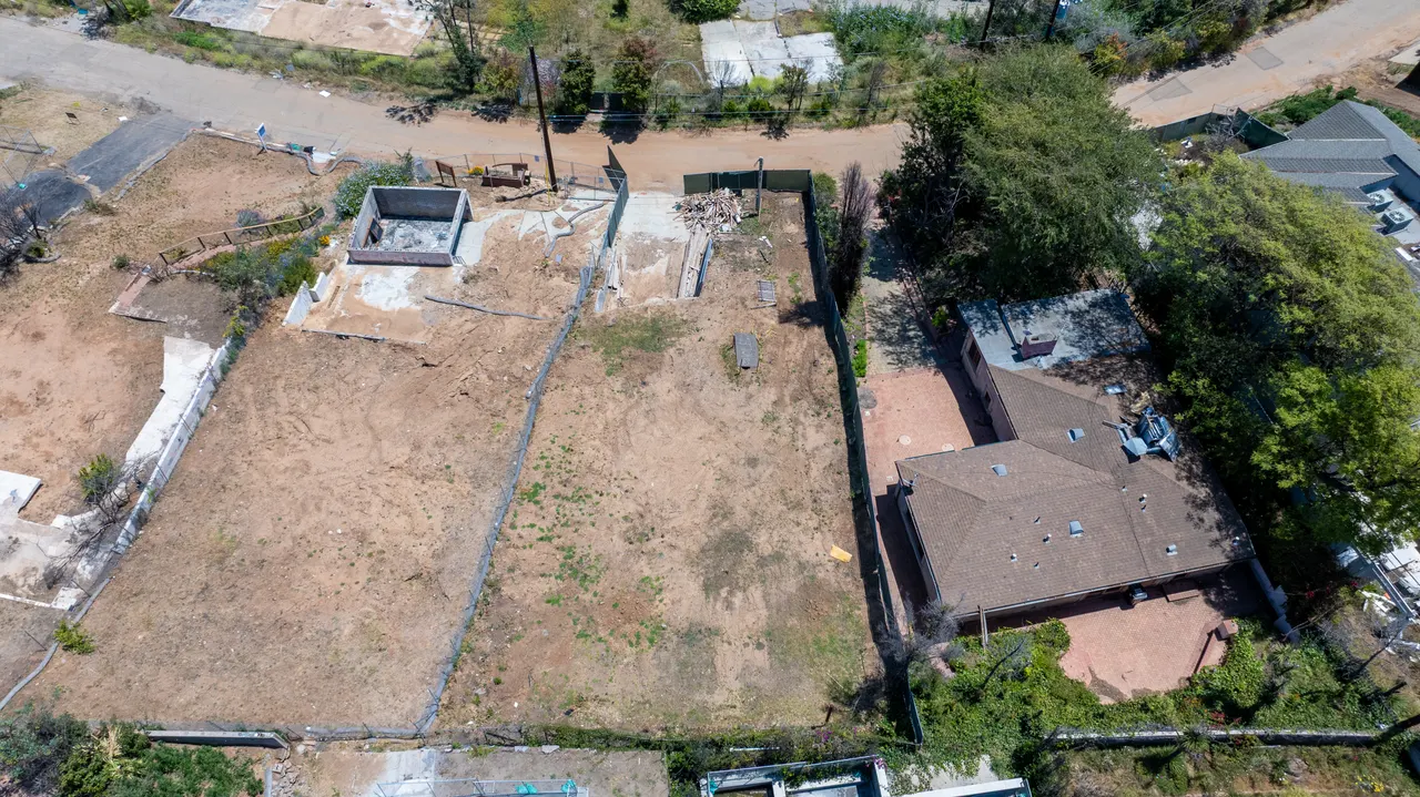 Aerial view of the graded lot from the street side, showing the driveway approach, surrounding cul-de-sac, and neighboring properties