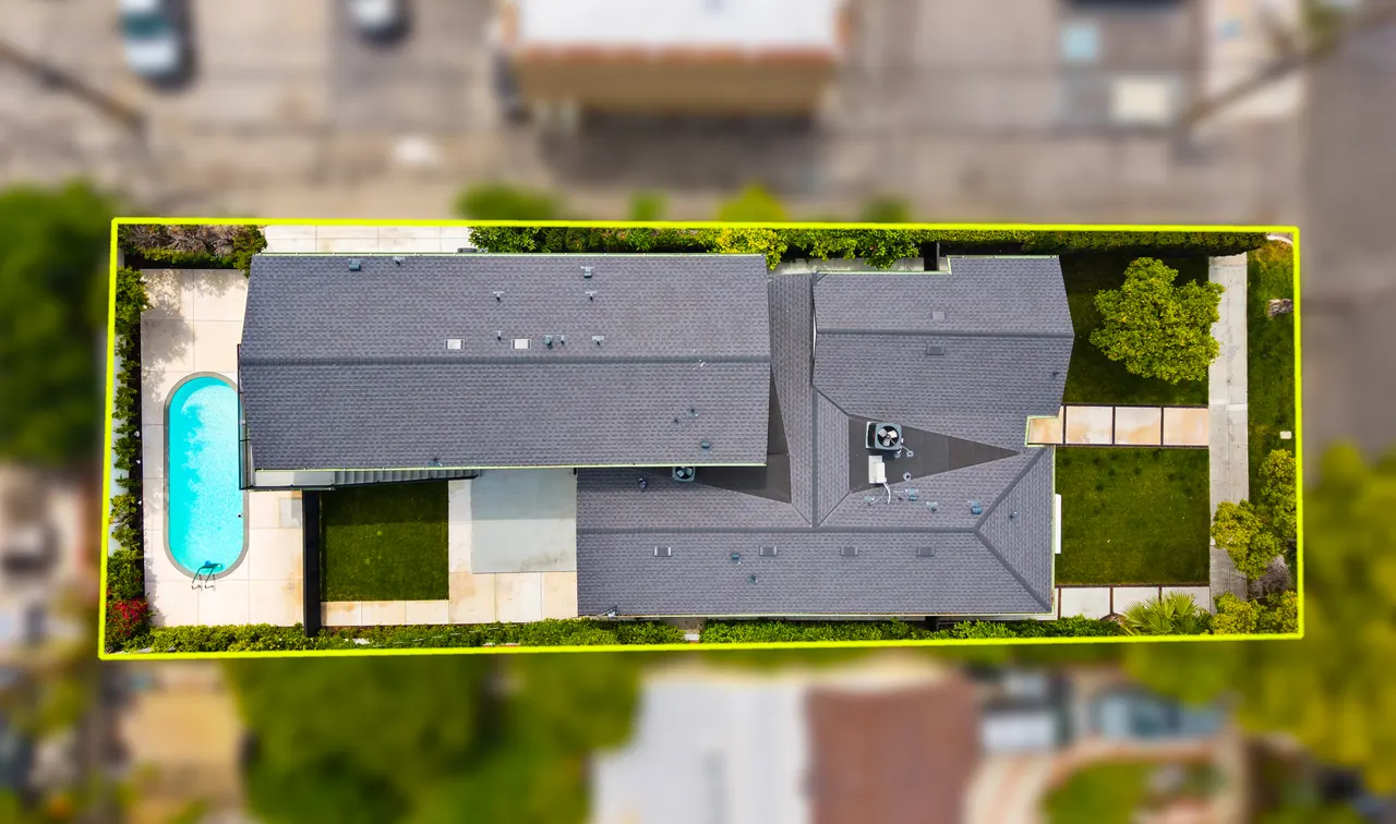 Straight-down aerial view of the property with a yellow boundary line, showing the roofline, backyard pool, patio, and landscaped yard