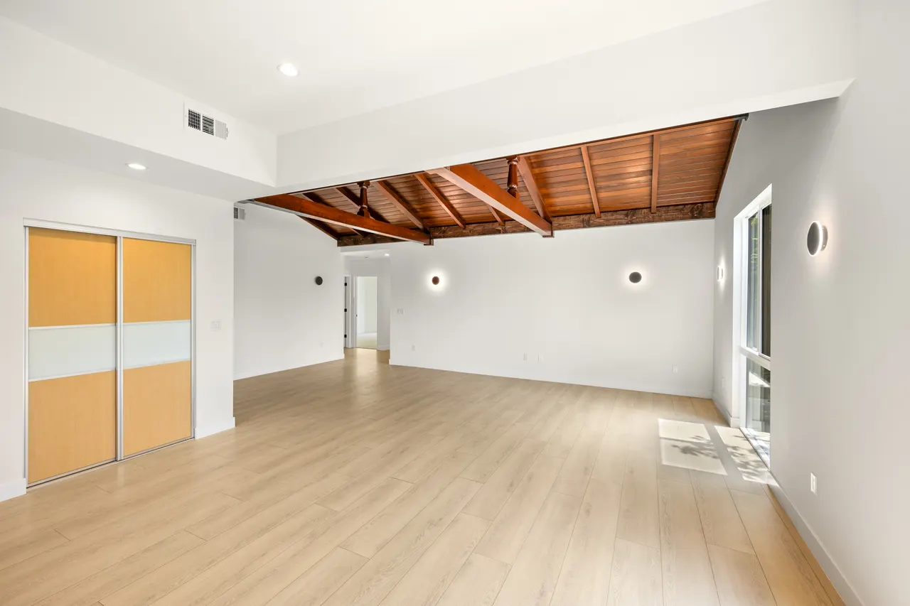 Bright room with a vaulted wood ceiling accent, wood-and-frosted-glass sliding closet doors, and light wood flooring