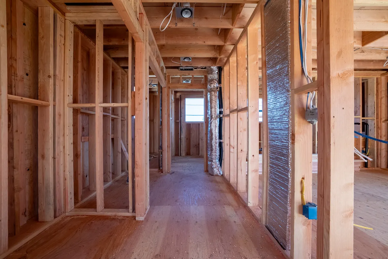 Framed hallway detail showing stud bays, wrapped ductwork, and rough electrical