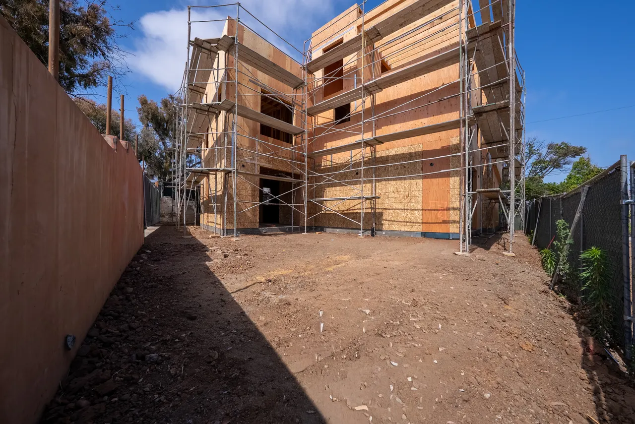 Plywood-sheathed exterior shell of the new custom home wrapped in scaffolding during construction