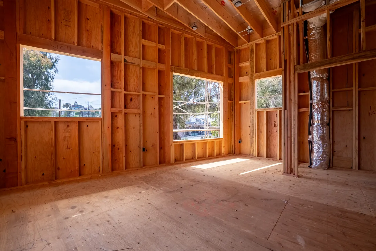 Vaulted wood-framed room with three window openings looking out to trees and the neighborhood