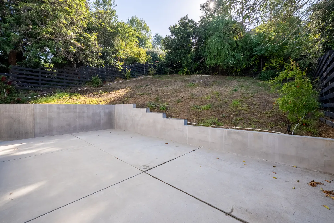 Concrete backyard patio set against the landscaped hillside