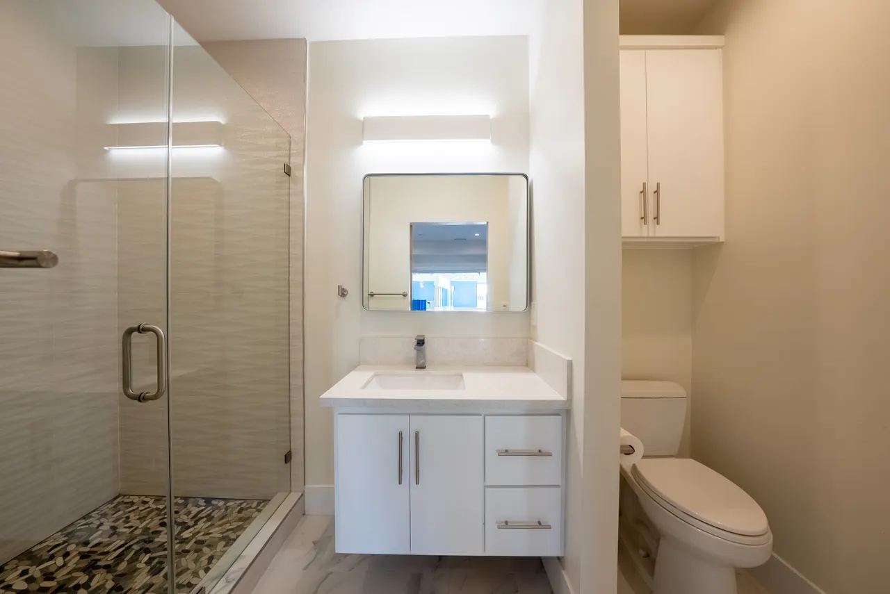 Full bathroom with glass shower, pebble floor, and floating vanity