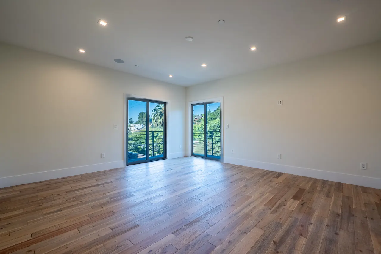 Bright bedroom with corner windows and wood floors