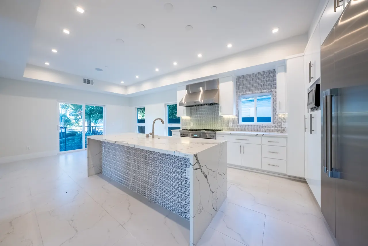 Chef's kitchen with waterfall marble island, professional range, and built-in refrigerator