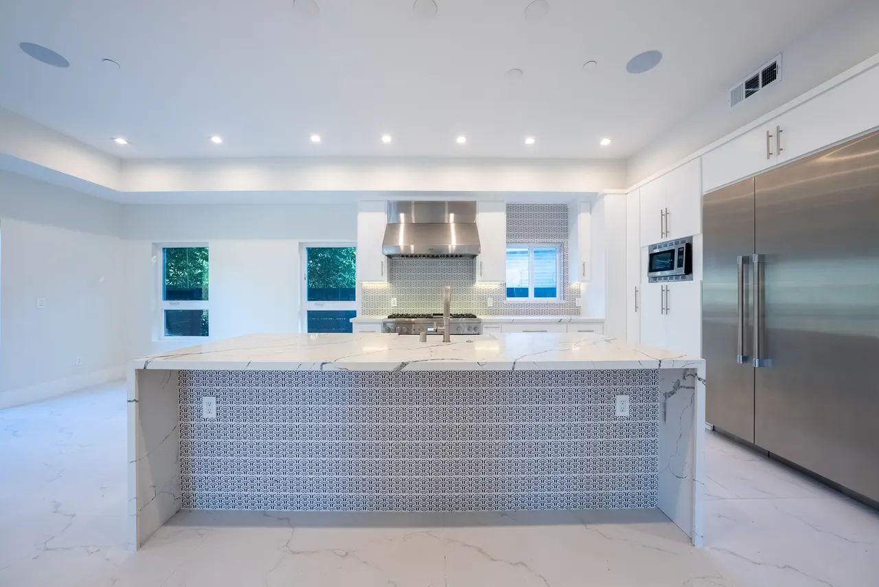 Kitchen island with patterned tile backsplash and stainless appliances