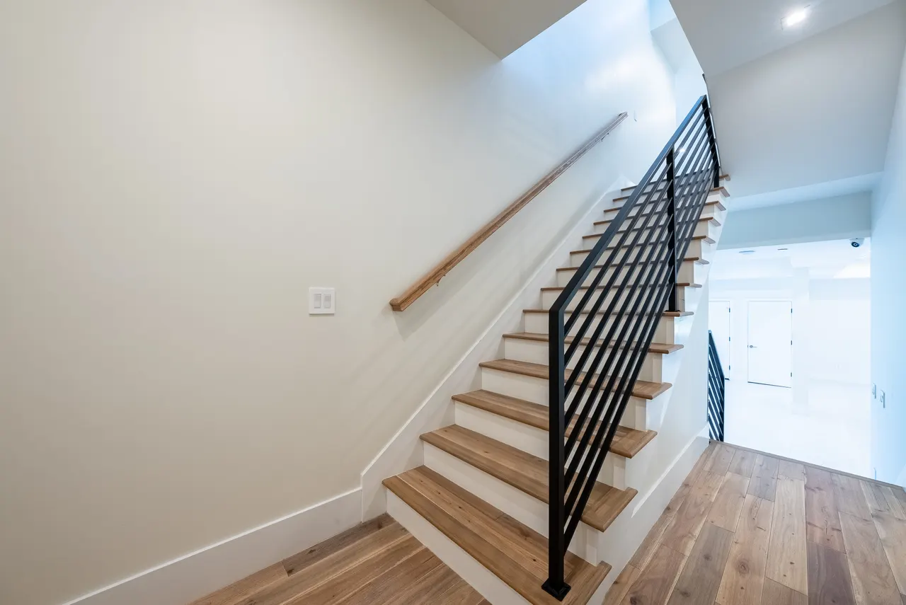Open-riser wood staircase with black metal railing